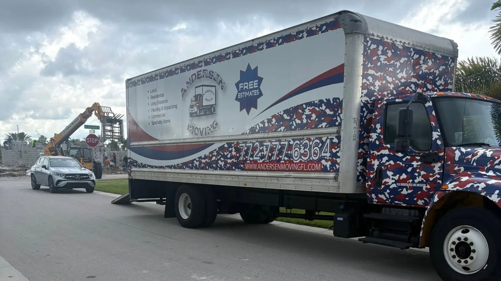 Andersen Moving box truck with its ramp down on a Port St. Lucie street beside a community under construction.